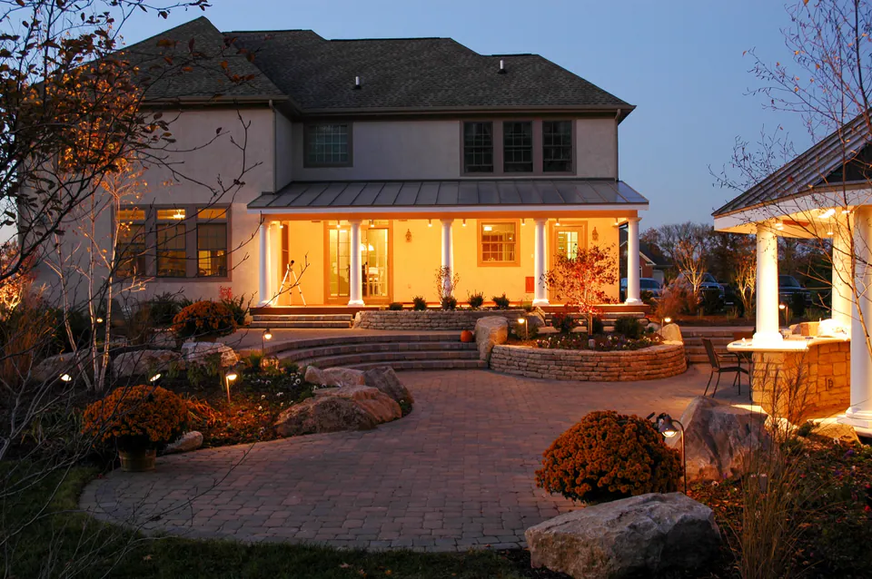Twilight patio courtyard with path lights, lit planting beds, stone steps, and warm architectural lighting